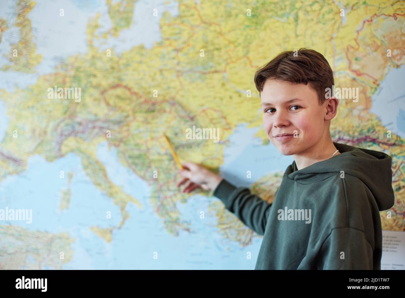 Ritratto di ragazzo che punta sulla mappa in classe Foto Stock