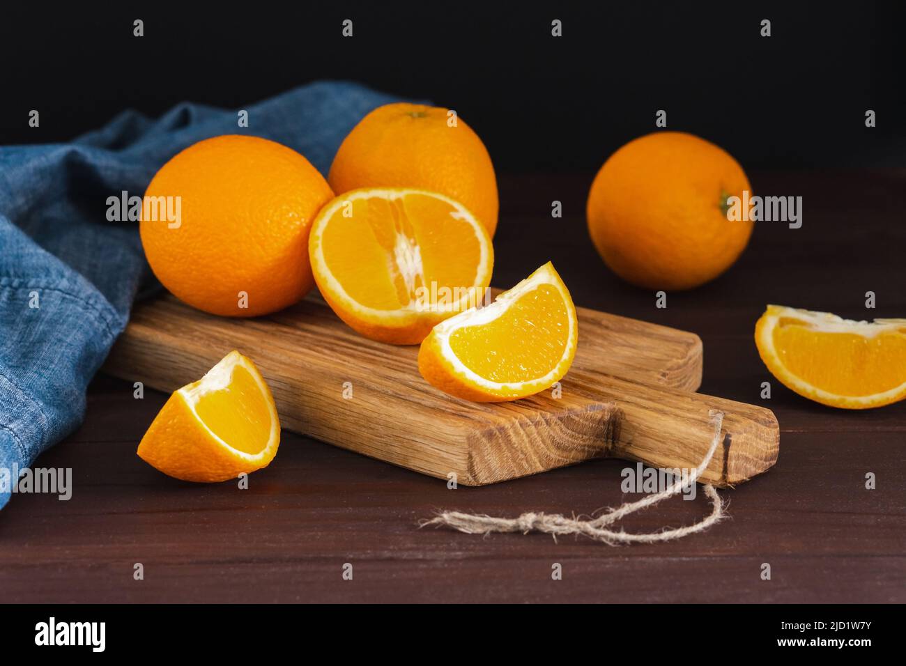 Arance a fette fruttate vicino al tessuto denim su asse di legno. Frutta succosa all'arancia, concetto minimo di agrumi Foto Stock