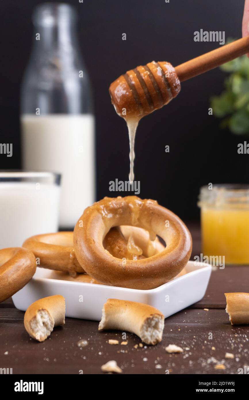 Tradizionali bagel con snack russi con latte e miele su un tavolo di legno. Dolce di farina popolare Foto Stock