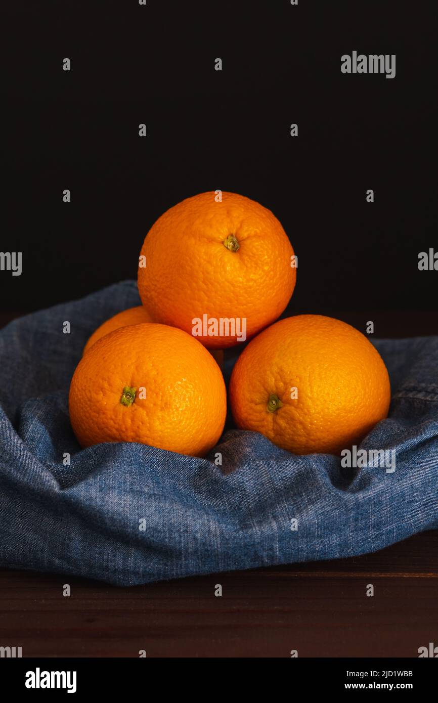 Arance frutta vicino denim tessuto su tavola scura. Frutta succosa all'arancia, concetto minimo di agrumi Foto Stock