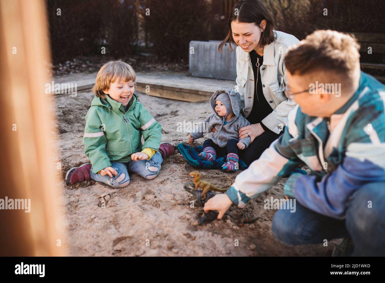 Famiglia con bambini che giocano in sandpit Foto Stock