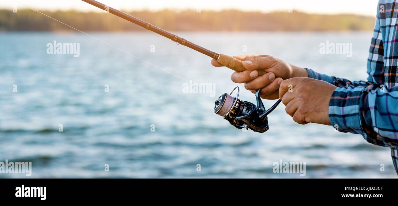 pescatore recuperare la linea di mulinello da pesca primo piano. banner con spazio copia Foto Stock