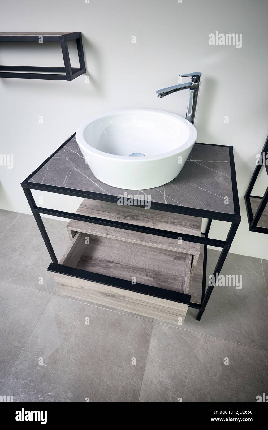Bagno in gres con pavimento piastrellato in gres beton. Appartamento industriale grigio, bagno mansardato con moderno lavandino sul ripiano e legno Foto Stock
