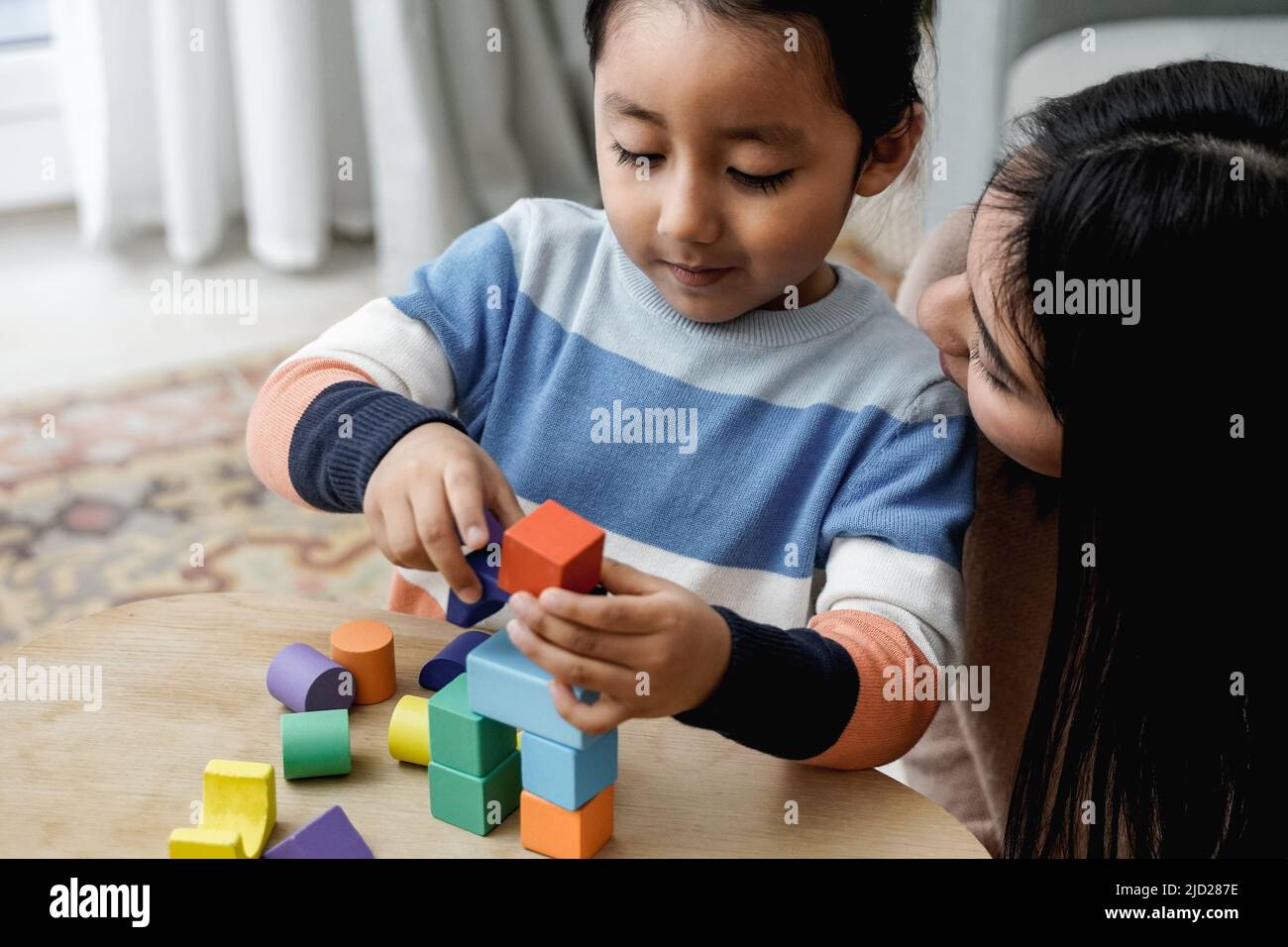 Madre e figlio latinoamericani divertirsi a giocare con i mattoni giocattolo a casa - concetto di amore per la famiglia - Focus sul volto del bambino Foto Stock