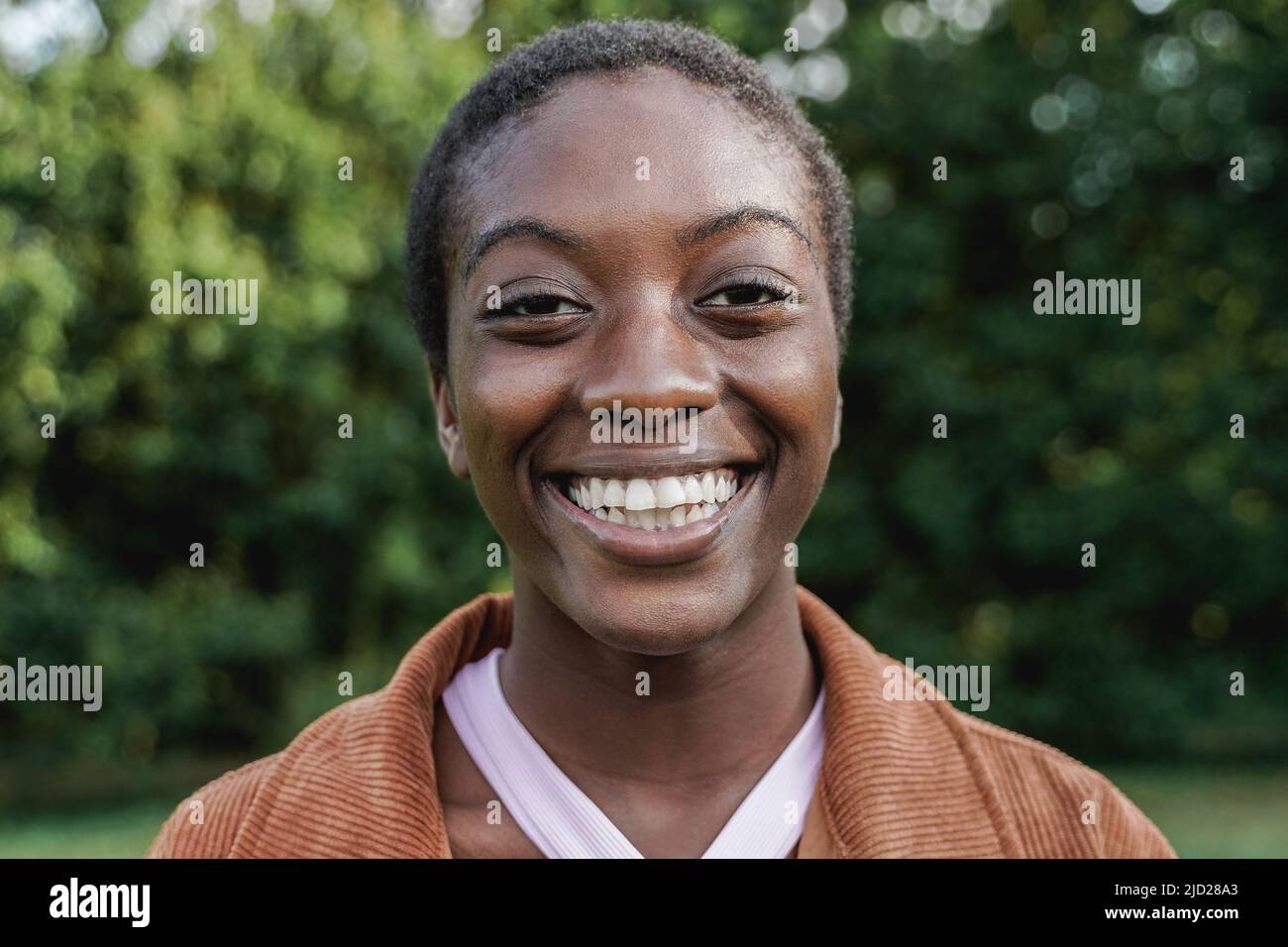 Felice ragazza calva africana sorridendo sulla macchina fotografica - fuoco sul volto Foto Stock