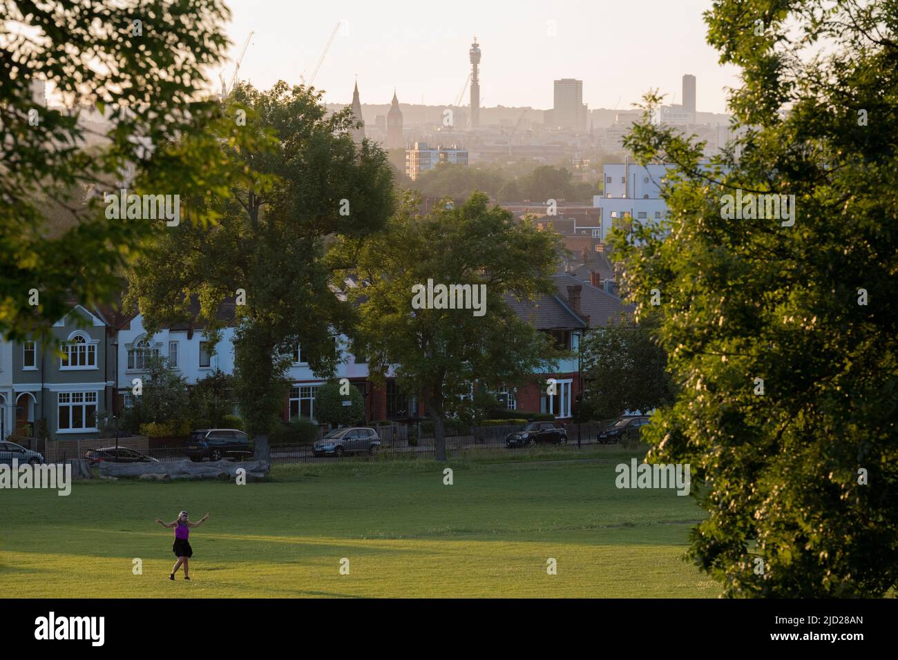 Una donna balla da sola con la sua musica in una serata estiva a Ruskin Park, uno spazio verde pubblico nel sud di Londra, il 11th giugno 2022, a Londra, Inghilterra. Foto Stock