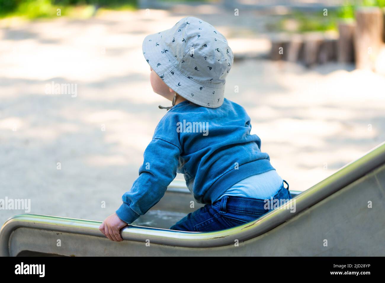 vista posteriore del bambino sullo scivolo, ragazzo di un anno che usa lo scivolo sul parco giochi Foto Stock