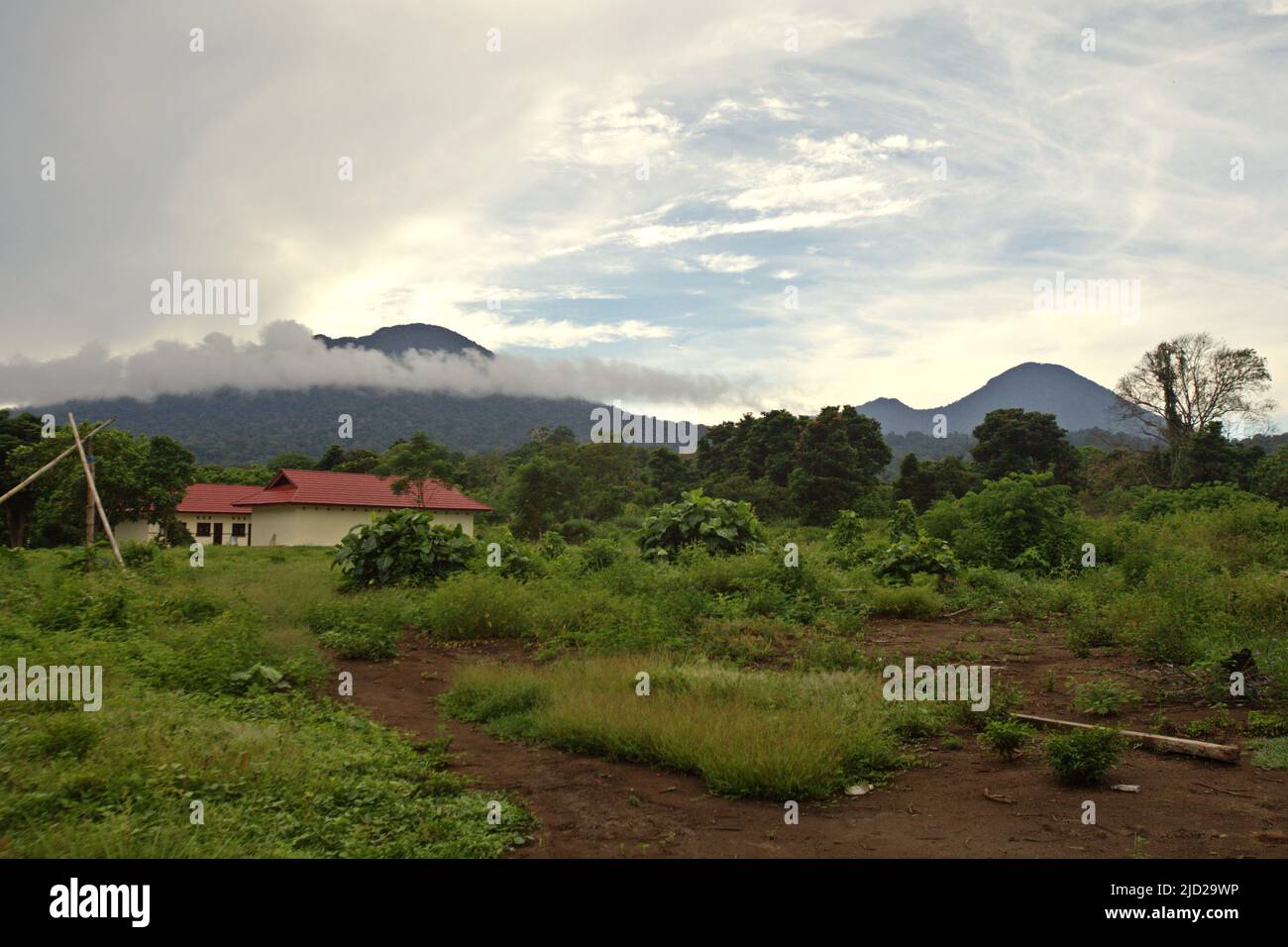 Monte Tangkoko (a sinistra) e Monte Dua Saudara che, insieme al Monte Batuangus (non raffigurato), sono le zone centrali della Riserva Naturale di Tangkoko Batuangus (Riserva Naturale di Tangkoko-Batuangus Dua Saudara), fotografata in primo piano di una struttura di gestione del turismo naturale a Nord Sulawesi, Indonesia. Foto Stock