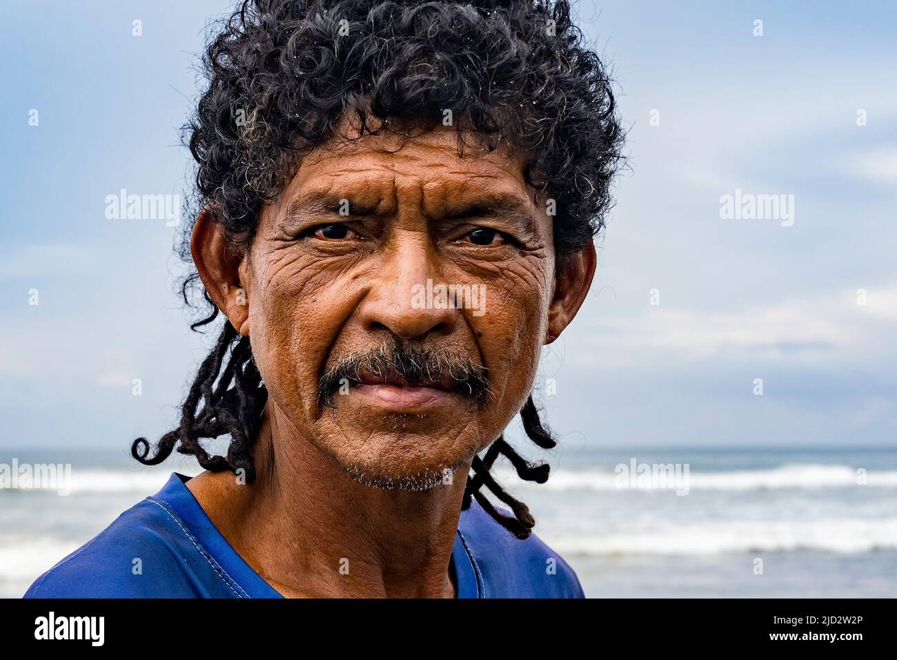 Primo piano di un pescatore nativo sulla riva con il mare sullo sfondo. Foto Stock