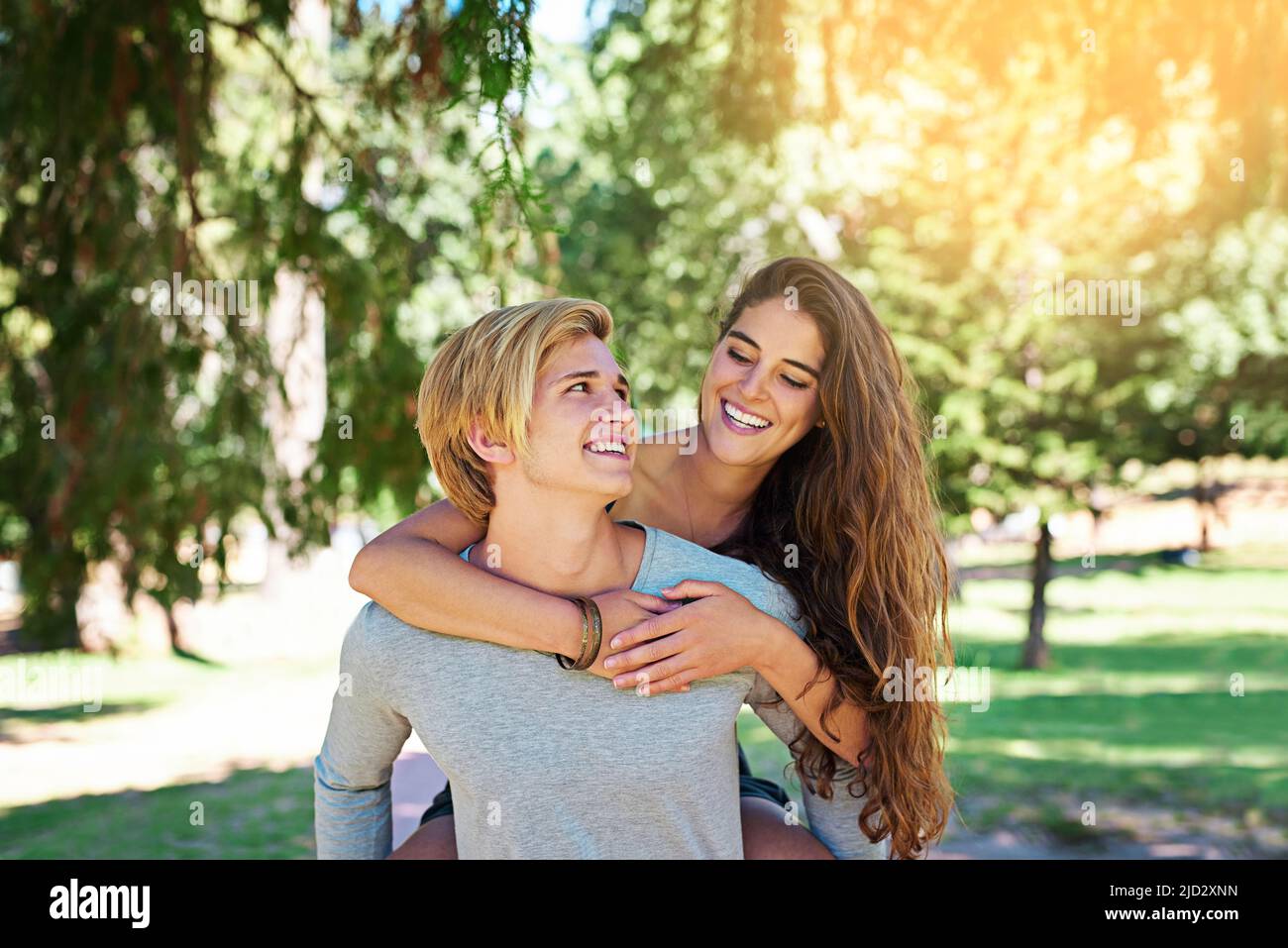 Dove per il prossimo, signora. Scatto di una giovane coppia felice godendo un giro di piggyback all'aperto. Foto Stock