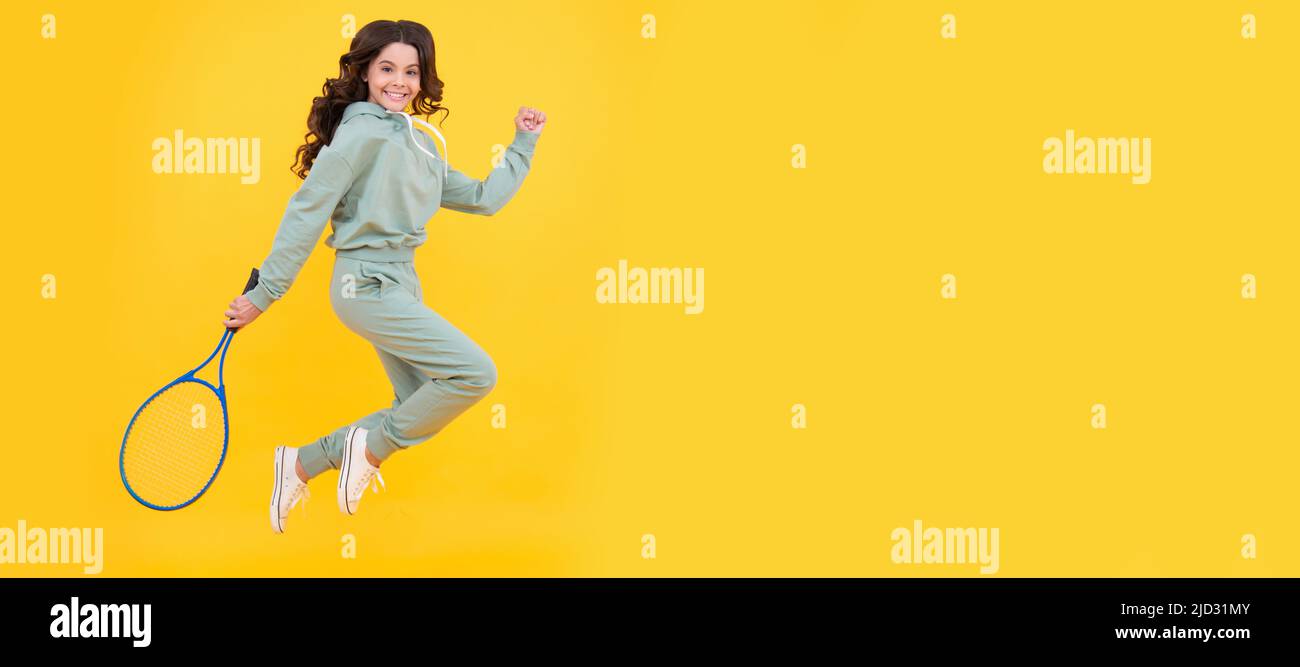 felice energico bambino salto in sportswear con racchetta da squash su sfondo giallo, successo sportivo. Poster orizzontale della faccia figlio isolata, banner Foto Stock