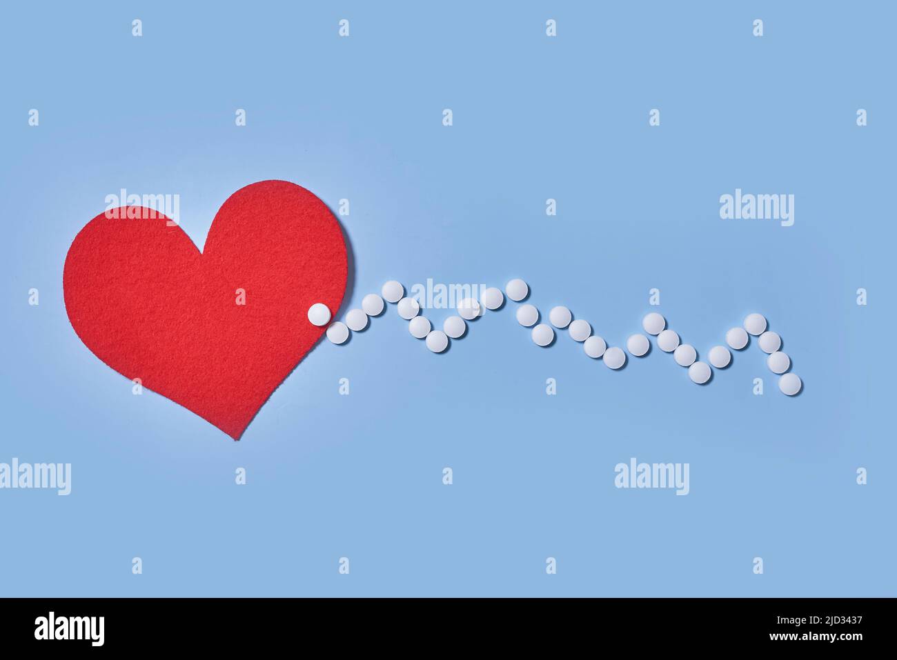 Medicina, salute e farmacia concetto - pillole e di farmaci in forma di cuore e ritmo cardiaco su sfondo blu Foto Stock