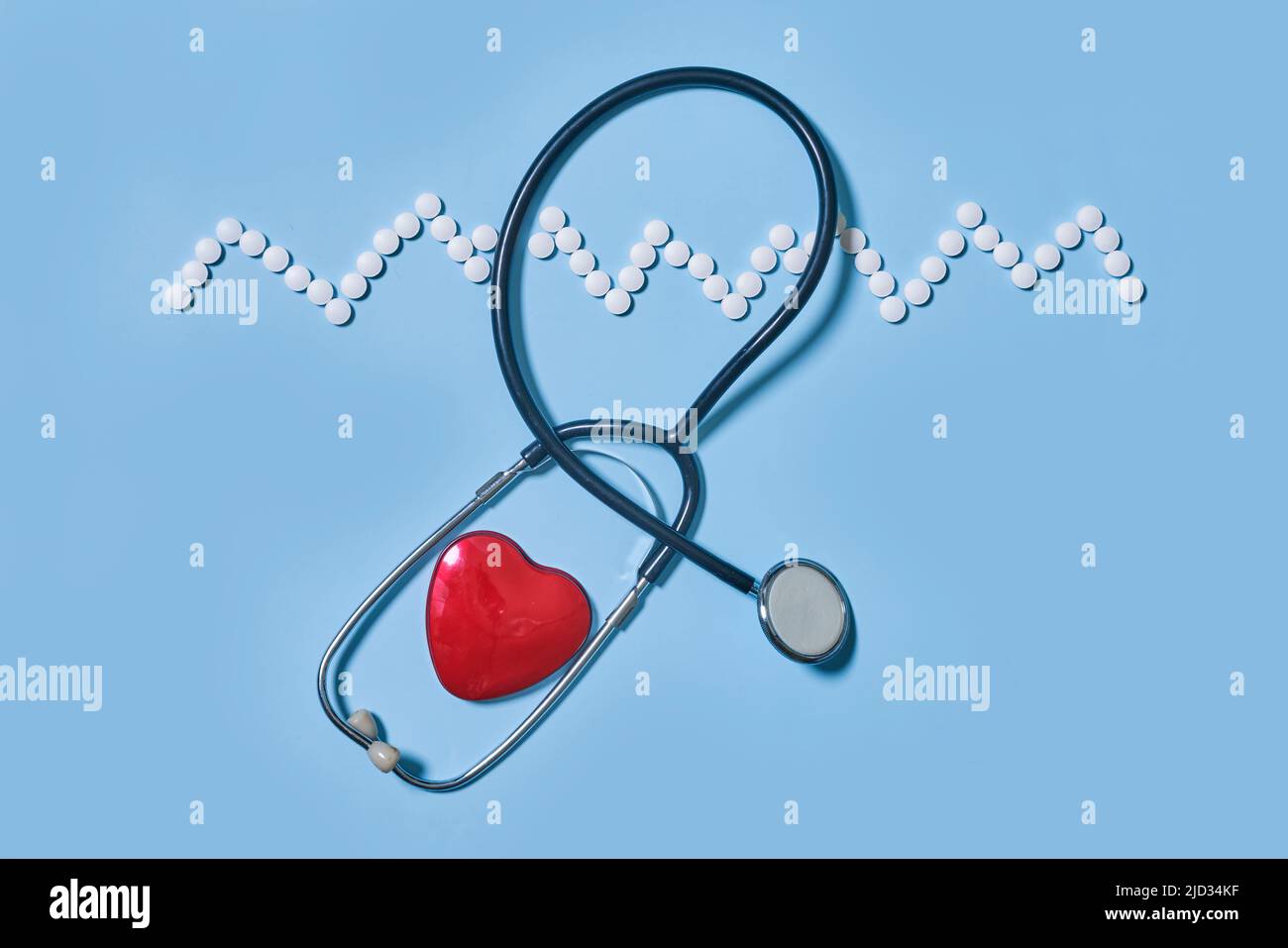Medicina, salute e farmacia concetto - pillole e di farmaci in forma di cuore e ritmo cardiaco e stetoscopio su sfondo blu Foto Stock