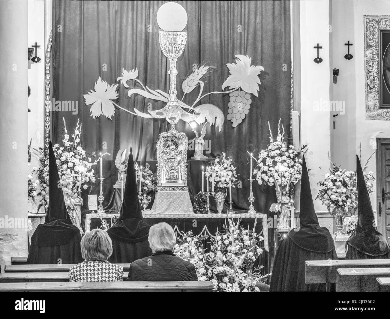 Quattro penitenti pregano all'interno di una chiesa di Úbeda Foto Stock