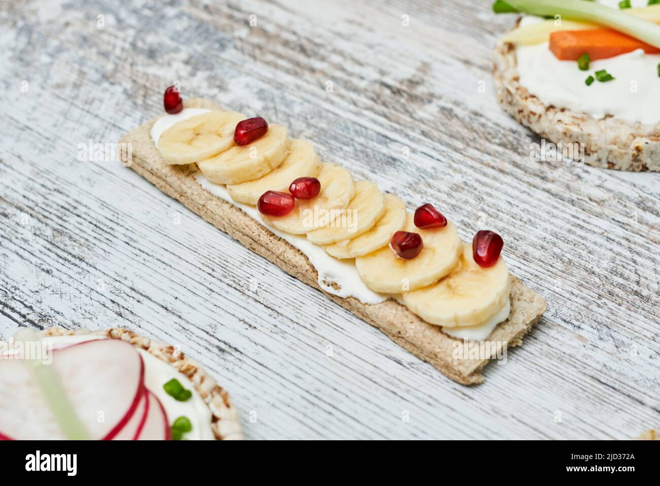 Croccanti con formaggio cremoso e frutta su sfondo bianco di legno Foto Stock