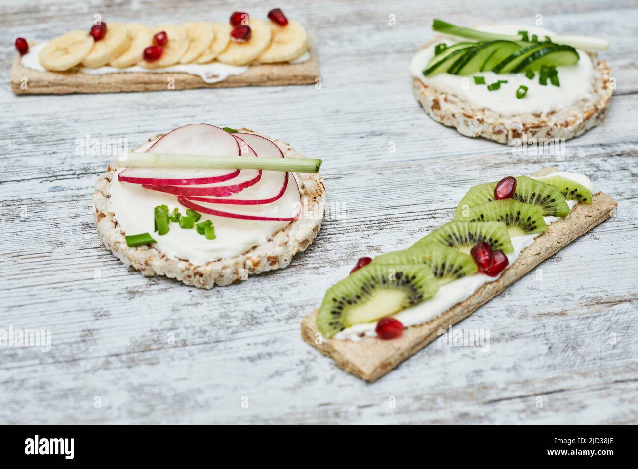 Torta di riso e croccanti con formaggio cremoso e verdure su tavola di legno Foto Stock