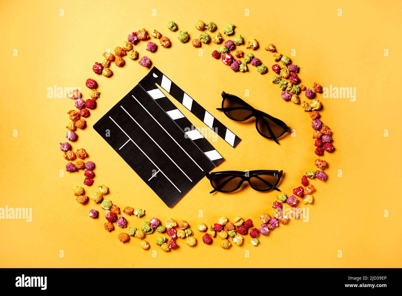 Film clapper, pop corn e 3D bicchieri su sfondo giallo. Disposizione piatta. Concetto di party cinematografico. Foto Stock