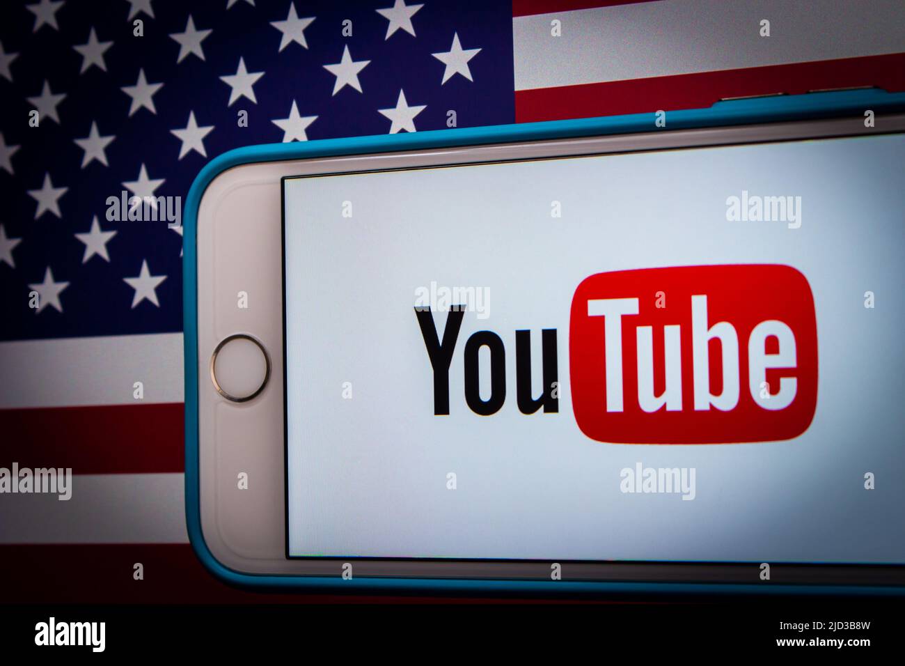 Kumamoto, GIAPPONE - Feb 22 2022 : l'immagine concettuale del logo di YouTube su un iPhone su sfondo di una bandiera americana in un umore scuro Foto Stock