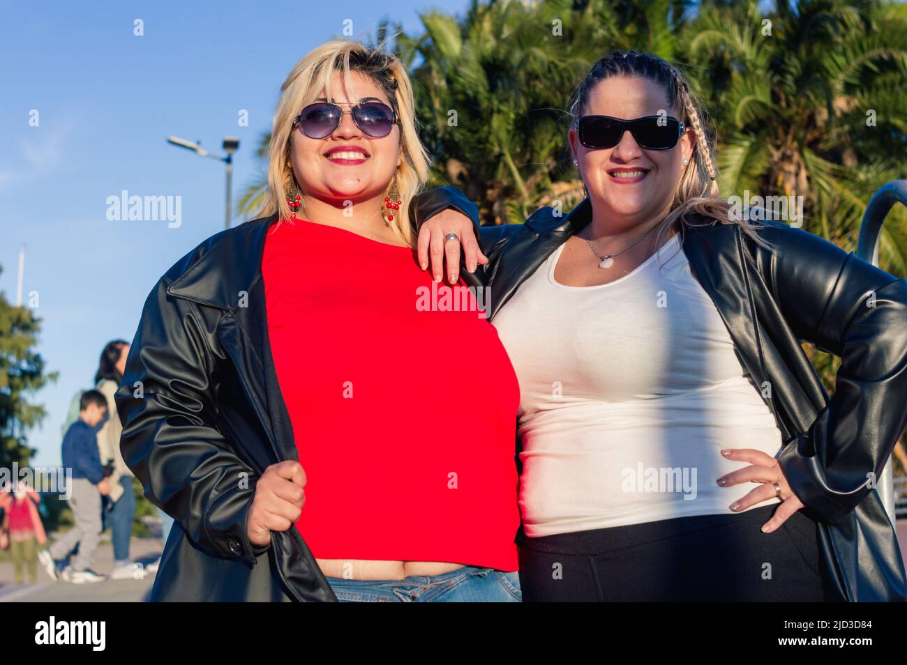 due belle donne caucasiche latino chubby, in posa di fronte alla macchina fotografica e guardando la macchina fotografica, sorridendo con occhiali da sole e abiti casual, lifes Foto Stock