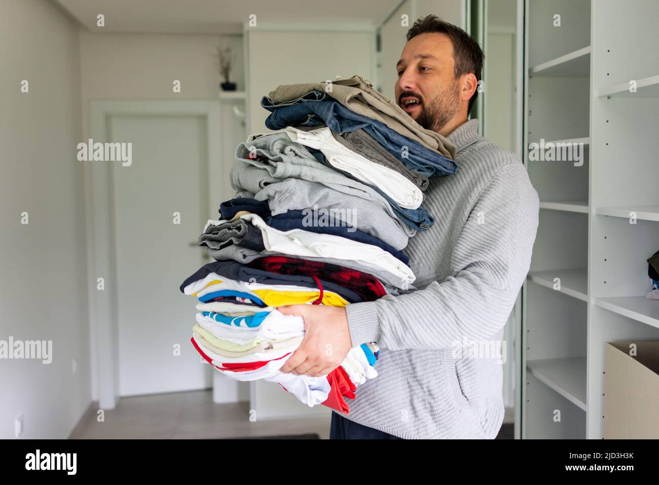 Uomo vestito danding da grande armadio armadio con abiti alla moda e roba casa. Foto di alta qualità Foto Stock