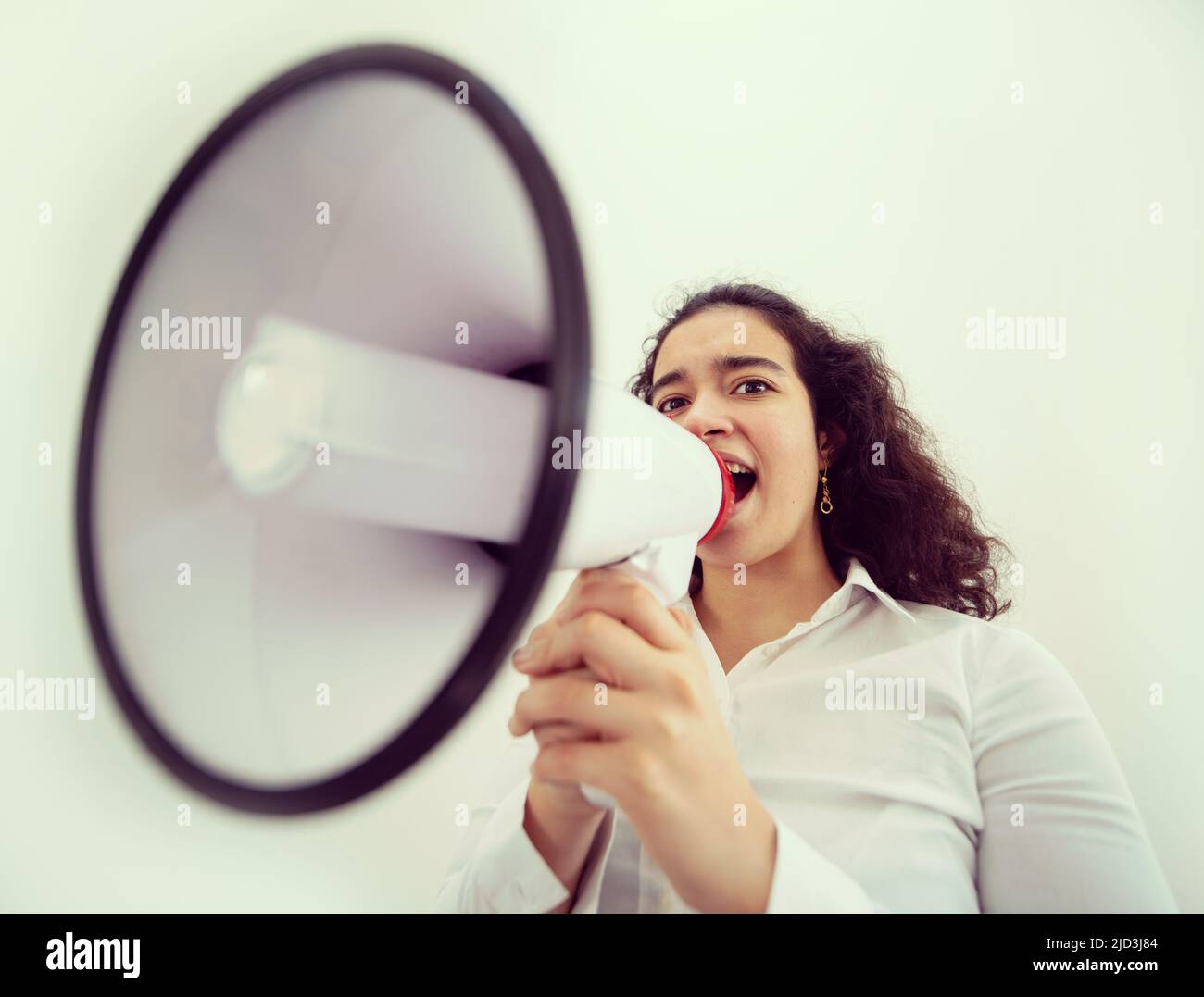 Bella donna d'affari con capelli ricci che tiene un megafono. Foto di alta qualità Foto Stock