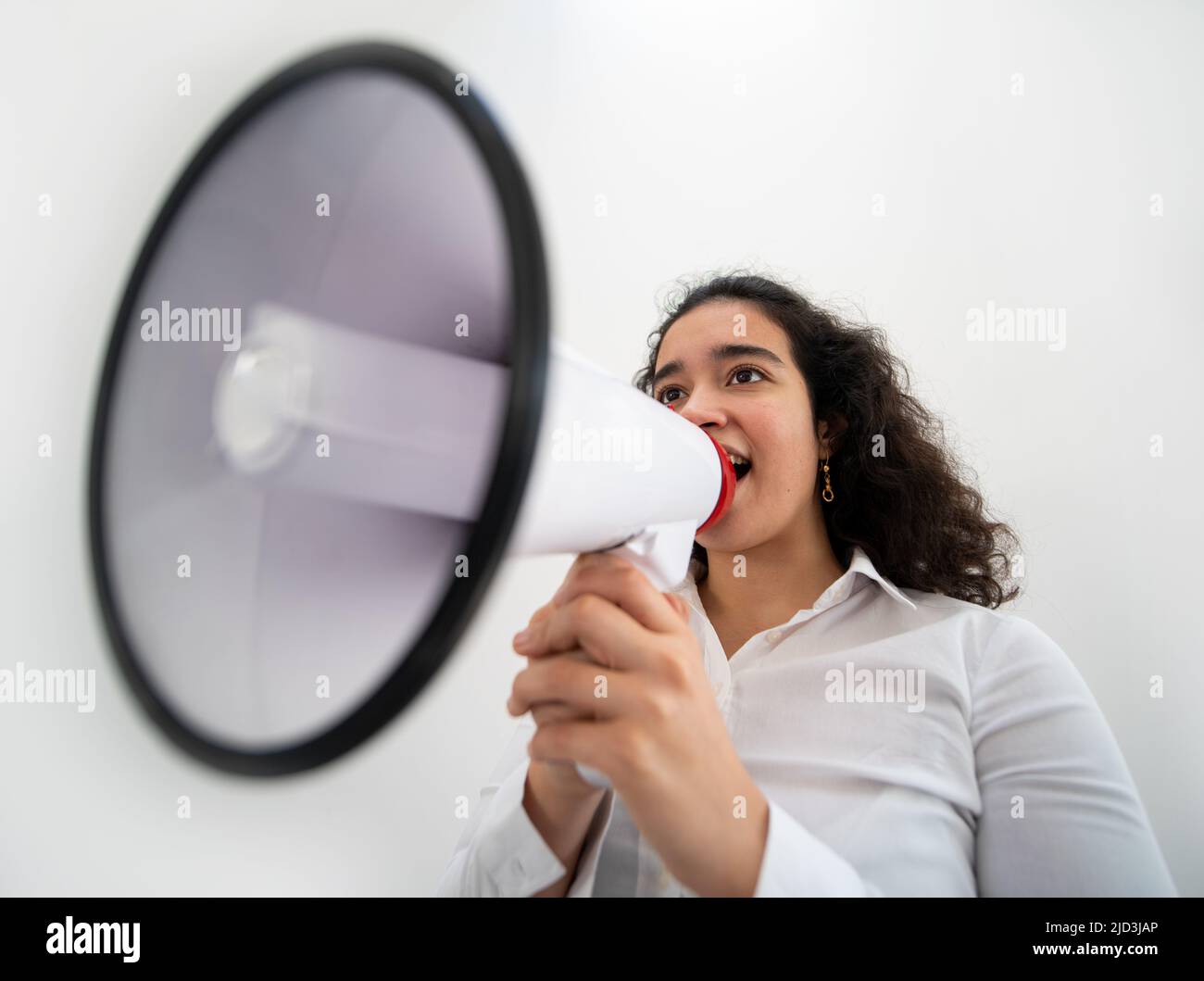 Bella donna d'affari con capelli ricci che tiene un megafono. Foto di alta qualità Foto Stock