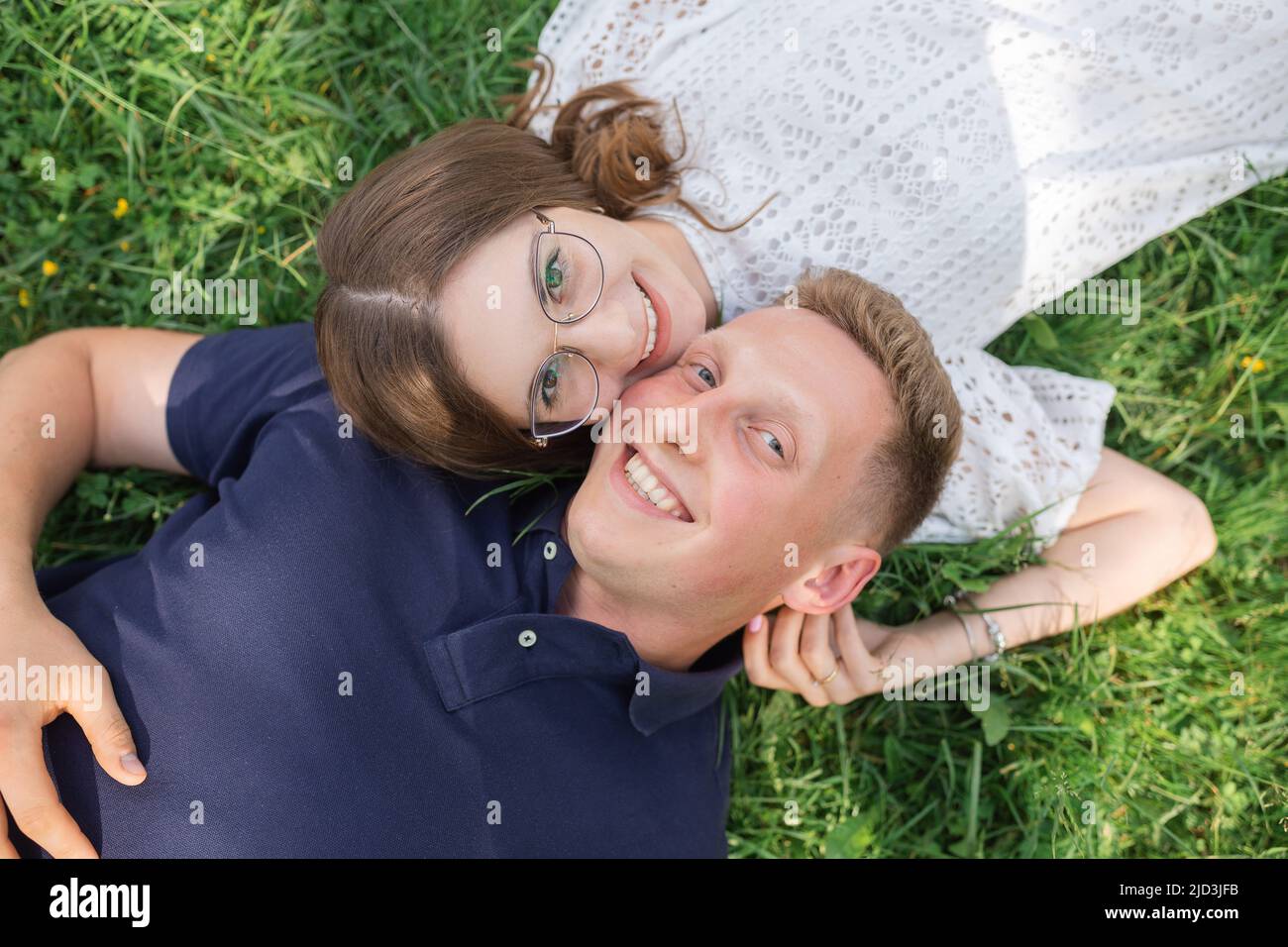 Divertimento estivo di uomo e donna. Vista dall'alto di una giovane coppia innamorata adagiata sull'erba e sorridente Foto Stock