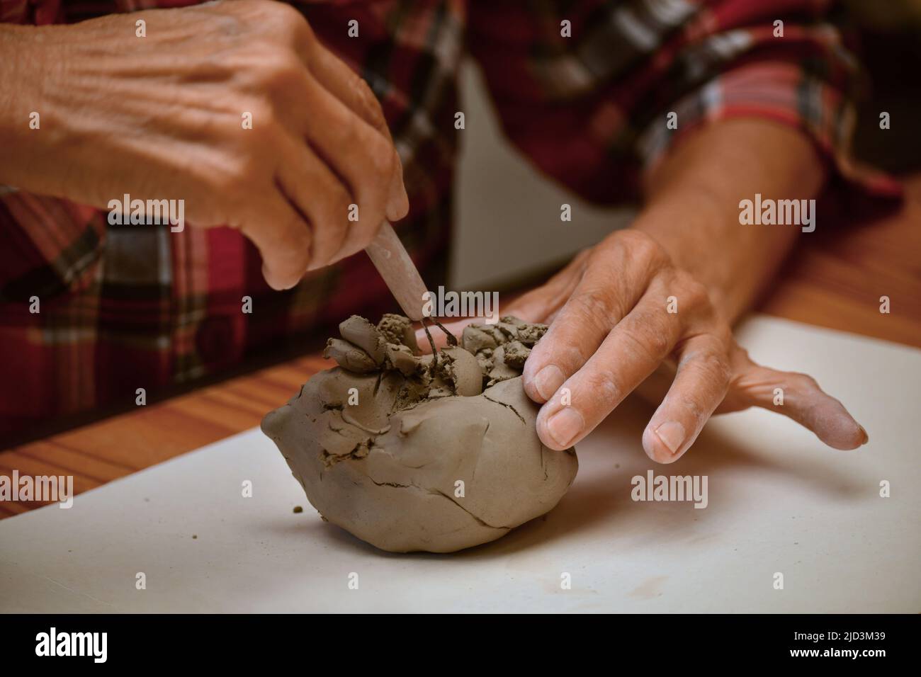 Vista ravvicinata di una donna anziana che forma un blocco di argilla e che fa una pentola di ceramica Foto Stock