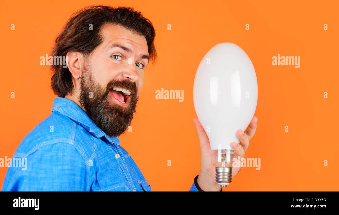 Bell'uomo con borsetta in camicia in denim con lampadina. Efficienza energetica ed elettricità. Buona idea Foto Stock