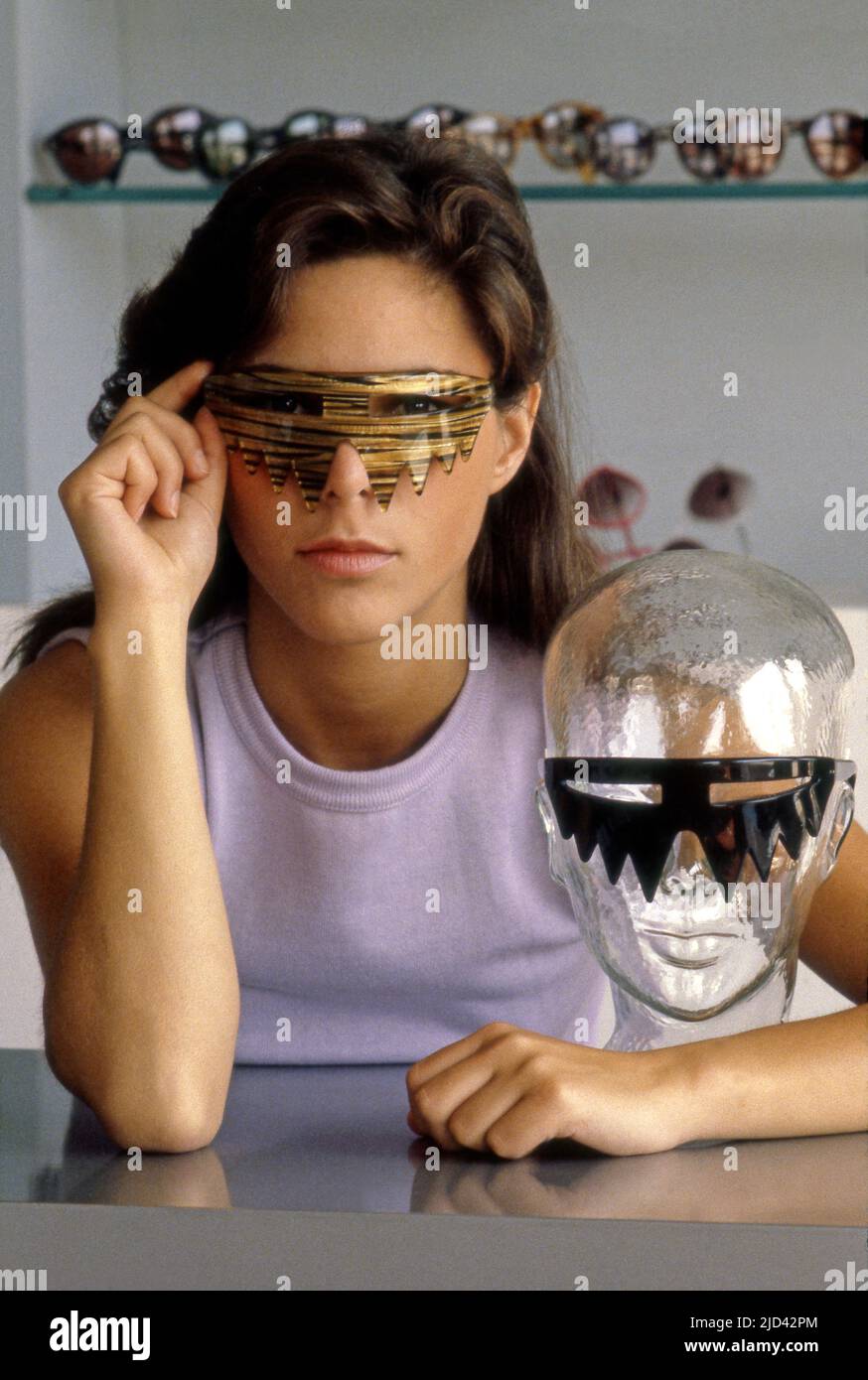 Una donna si pone in un paio di occhiali di anca a L.A. Eyeworks su Melrose Ave. A Los Angeles, CA, circa 1980s. Foto Stock