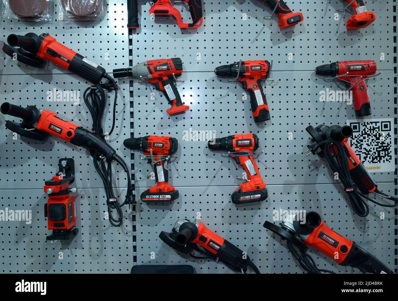 Trapani elettrici, cacciaviti cordless, chiavi, smerigliatrici portatili e altri utensili elettrici posizionati su un banco di un negozio. Esposizione industriale. Nov Foto Stock