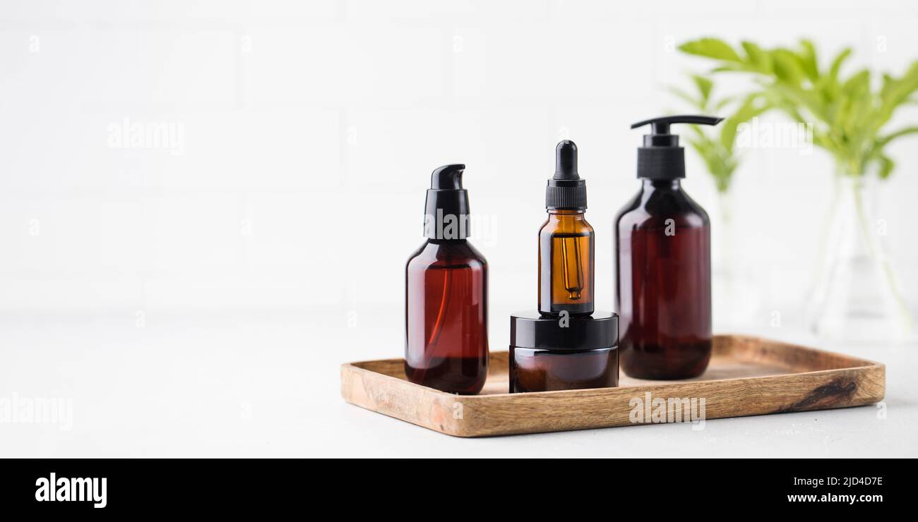 Vasetti cosmici e dispenser con cosmetici ecologici su vassoio di legno su sfondo chiaro. Spazio di copia. Foto Stock