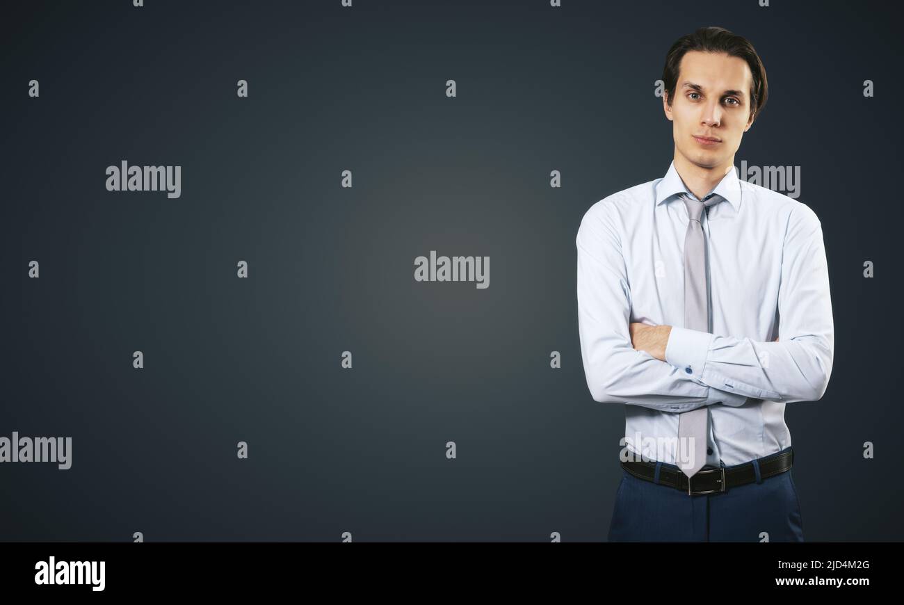 Concetto di successo aziendale con giovane uomo d'affari sorridente che piega le mani in camicia bianca e pantaloni blu scuro su sfondo nero astratto bianco Foto Stock