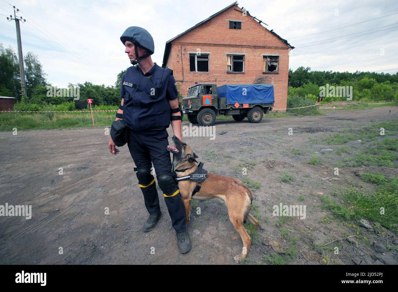 TROSTIANETS, UCRAINA - 17 GIUGNO 2022 - Un soccorritore ed un cane esplosivo di rivelazione rimangono in una pianta del mattone dove i lotti delle munizioni e dell'altra ite esplosiva Foto Stock