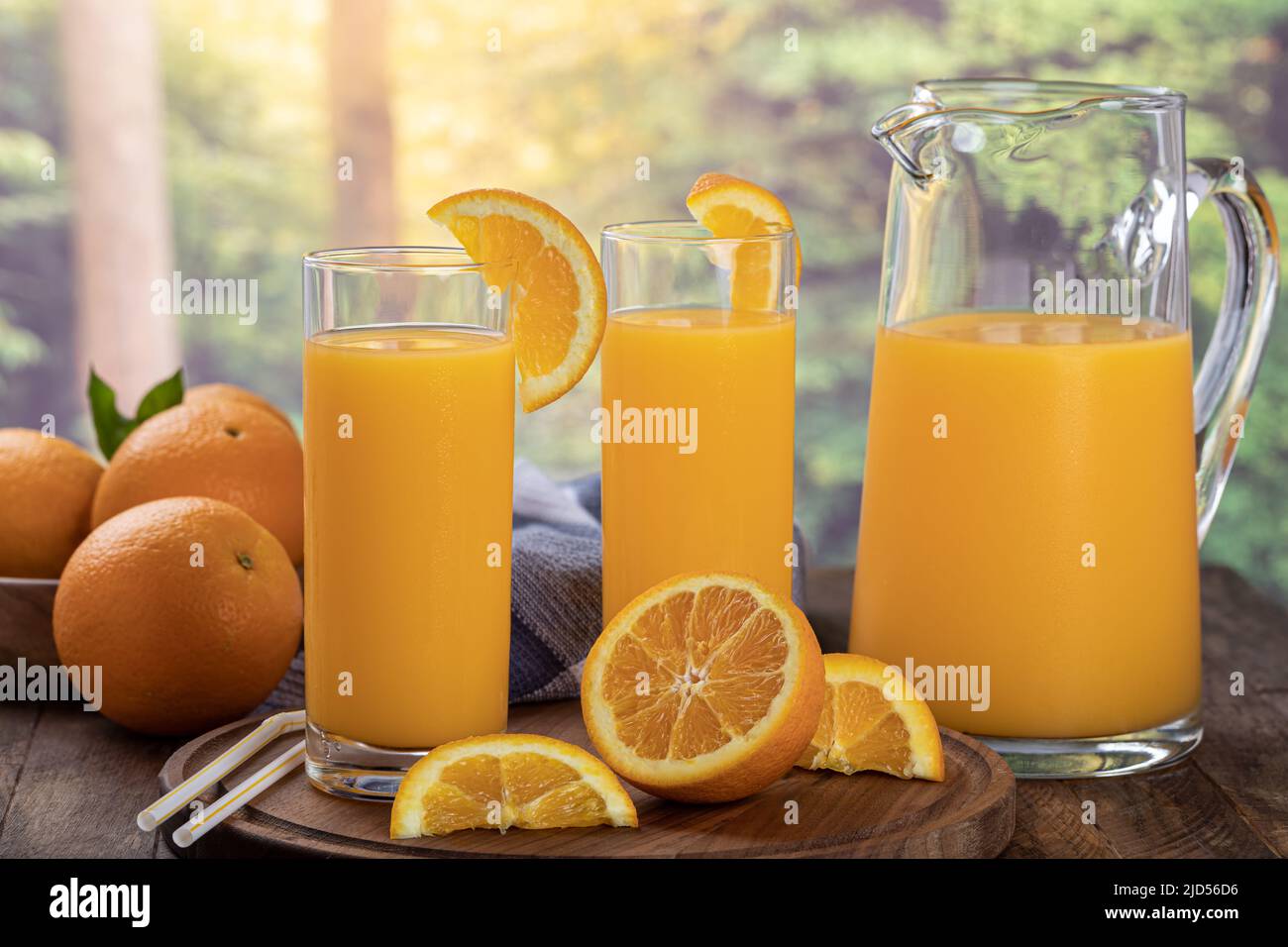 Due bicchieri e caraffa di succo d'arancia con arance a fette su sfondo rurale estivo Foto Stock
