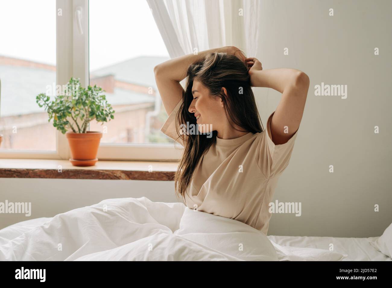 Una giovane donna europea che si sveglia al mattino si allunga e gode Foto Stock