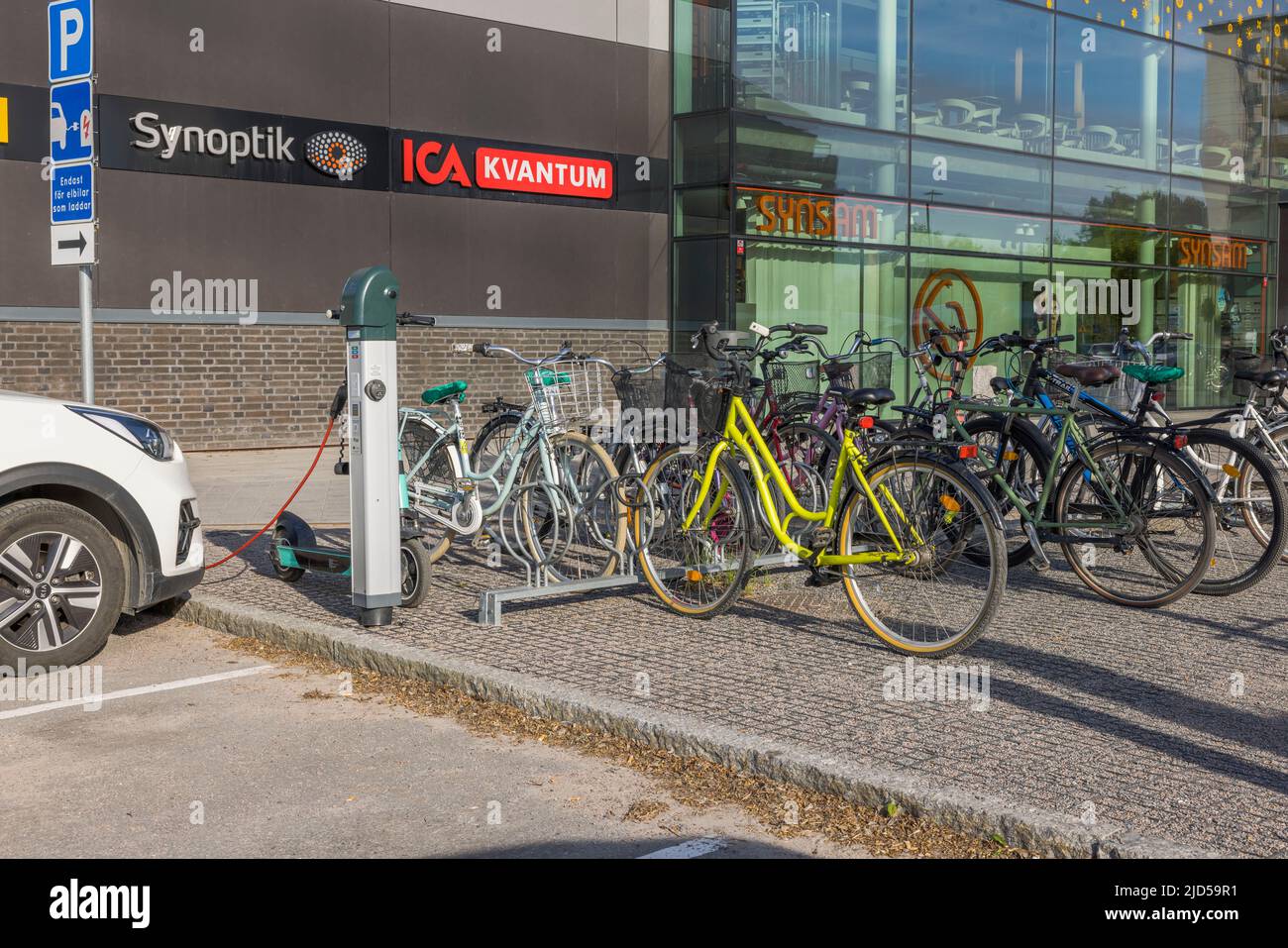 Parcheggio per biciclette e vista del cavo di ricarica collegato all'auto dalla stazione di ricarica di veicoli elettrici del centro commerciale della città di Uppsala. SWE Foto Stock