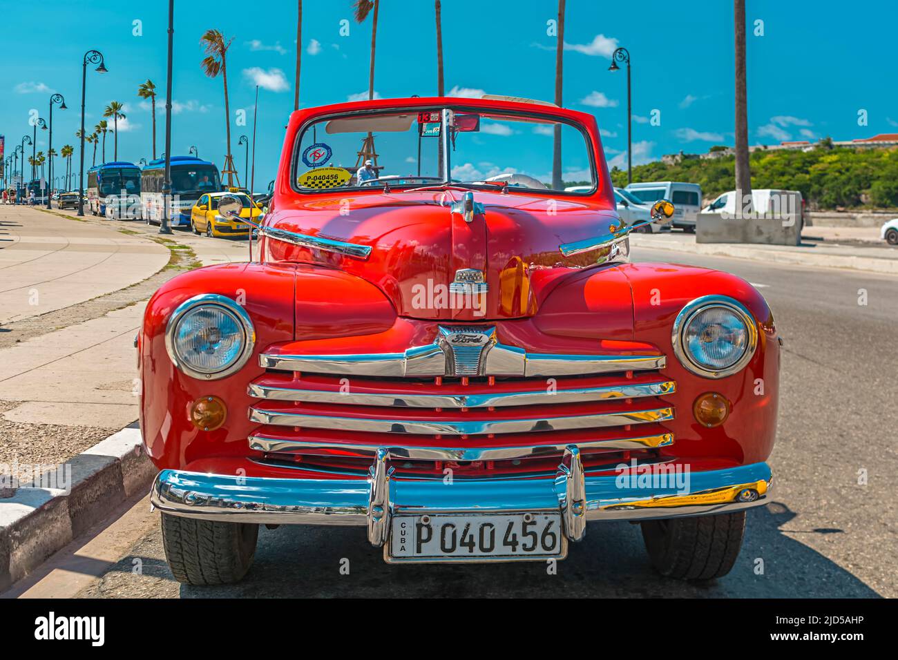Una bella auto d'epoca rossa parcheggiata sul famoso Malecon a l'Avana, Cuba Foto Stock
