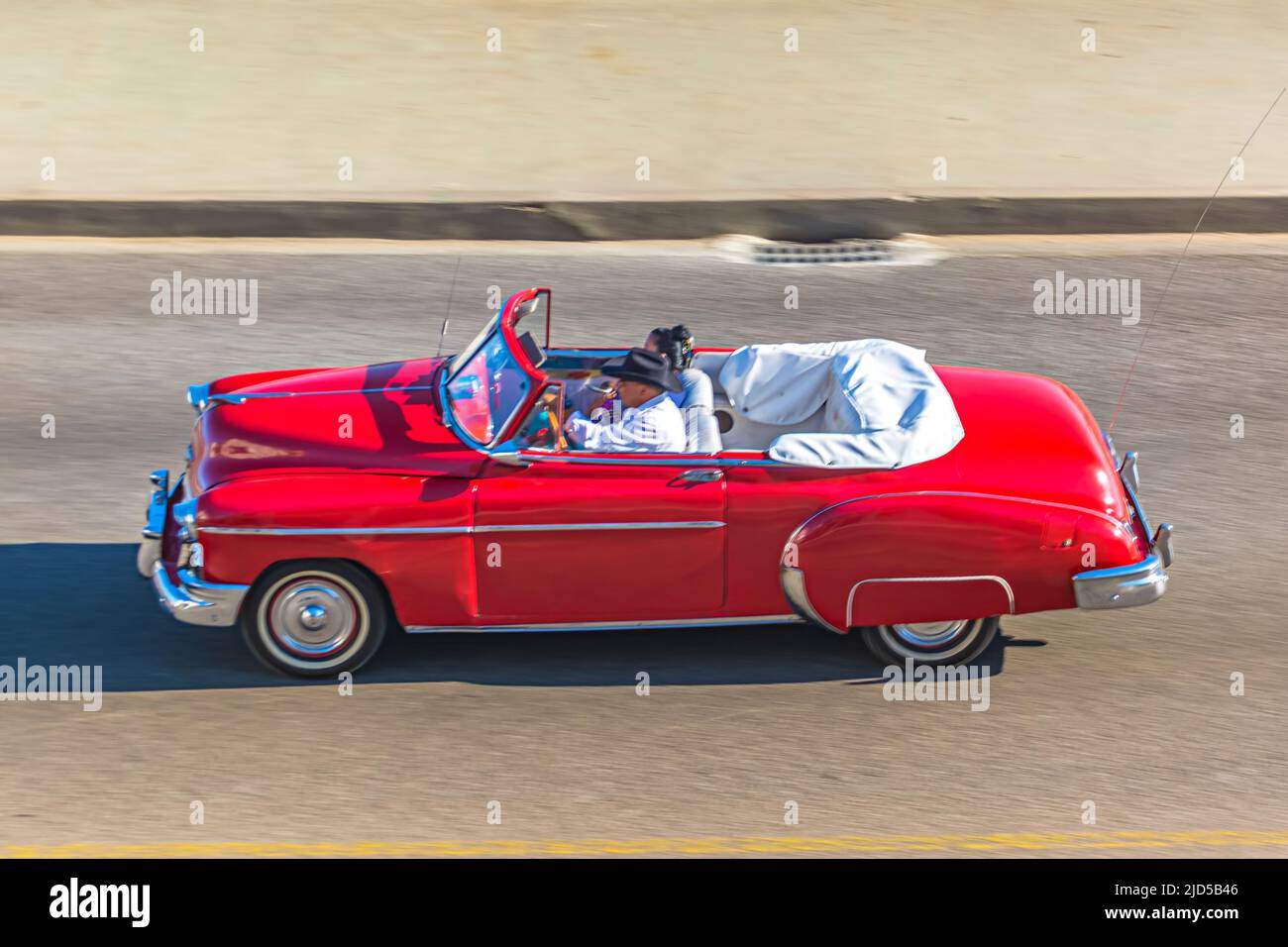Un'auto d'epoca rossa guida lungo il famoso Malecon a l'Avana, Cuba Foto Stock
