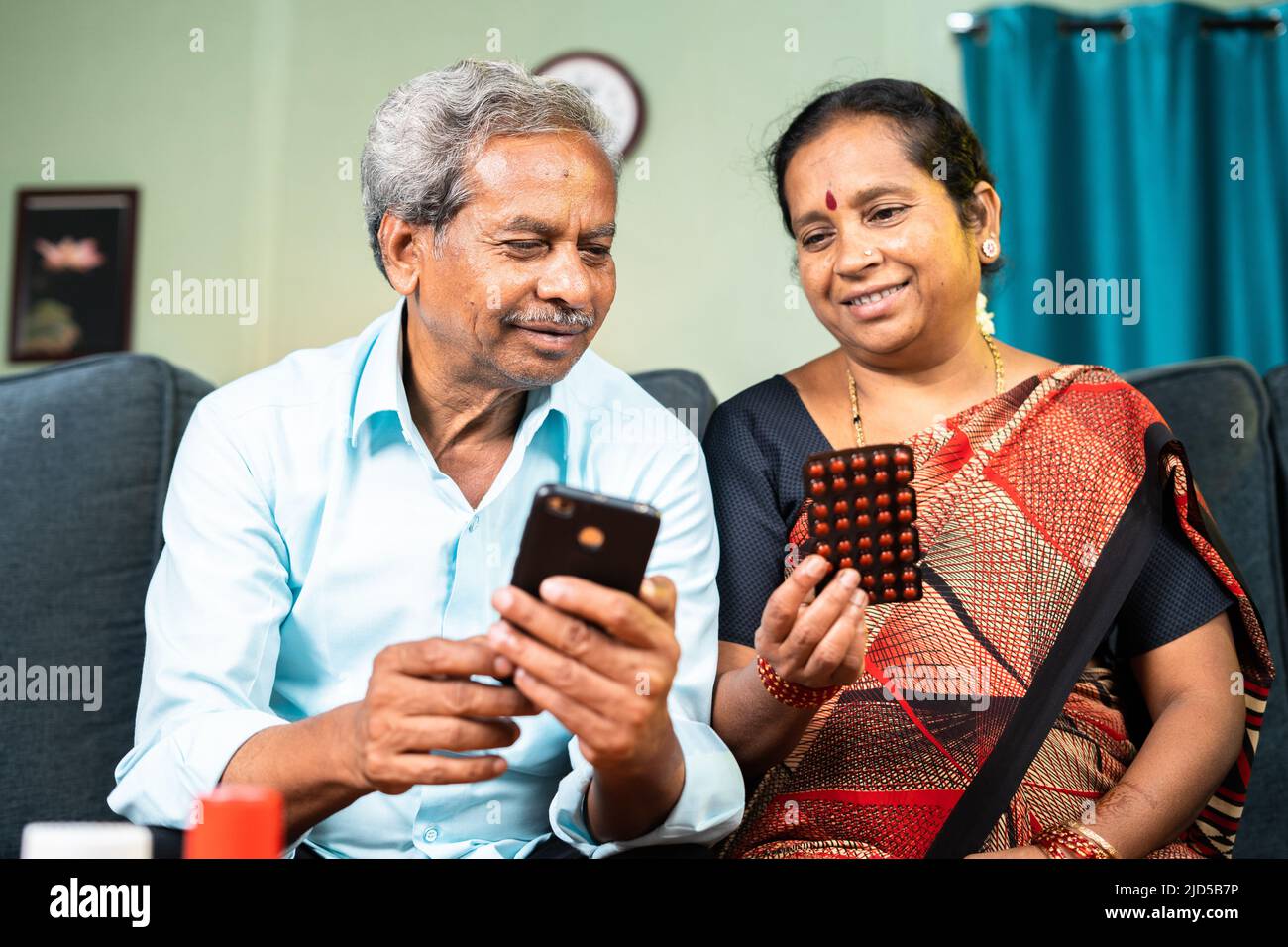 Senior vecchia coppia ordinare farmaci su applicazione cellulare mentre si siede sul divano a casa - concetto di sanità, tecnologia online ed e Foto Stock