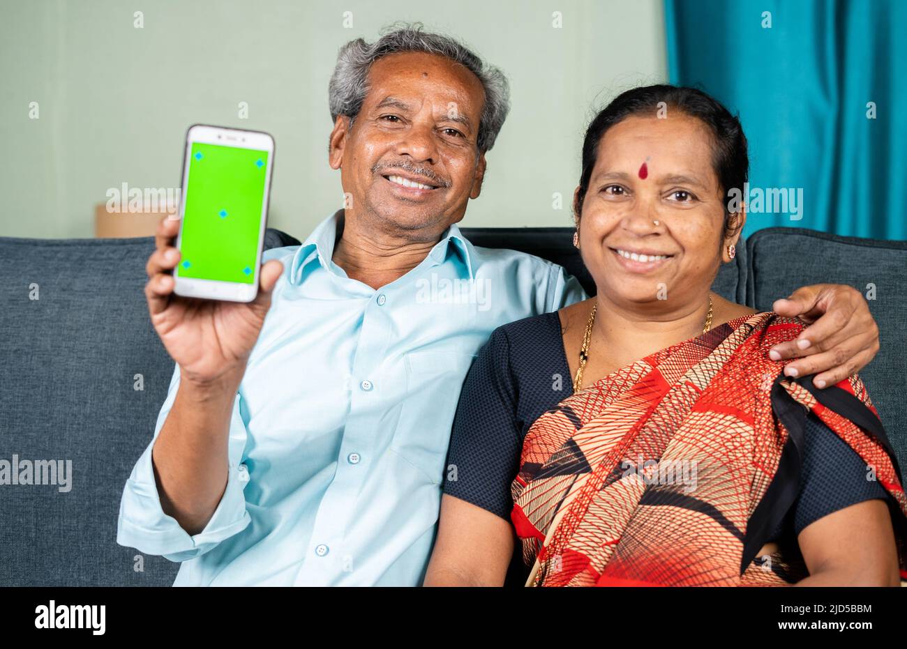 Felice sorridente coppia anziana che mostra telefono cellulare con schermo verde guardando la fotocamera - concetto di tecnologia, applicazione e Unione Foto Stock