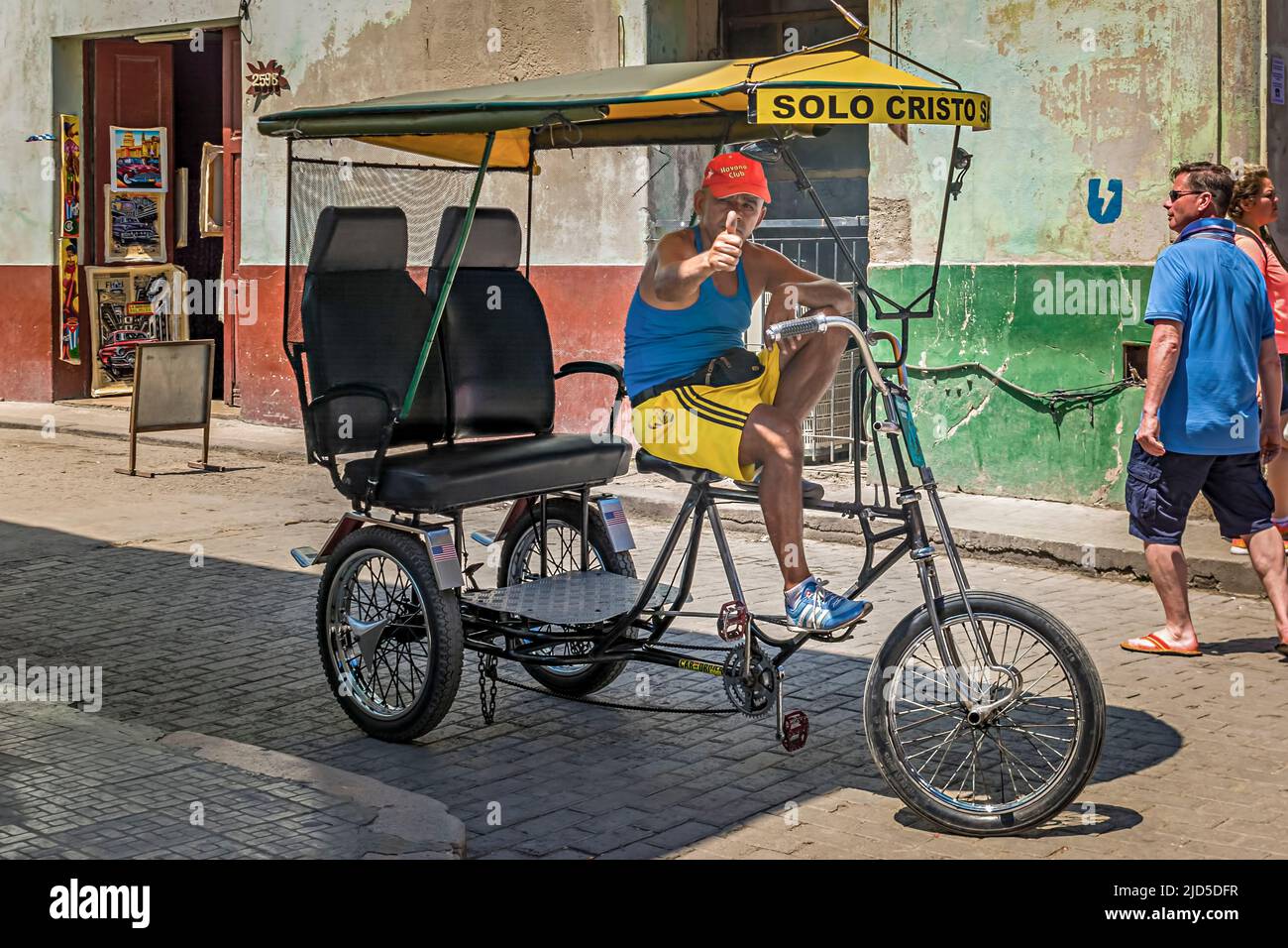 Un vecchio che guida il veicolo di trasporto più comune di Old Havana, un Bicitaxi Foto Stock