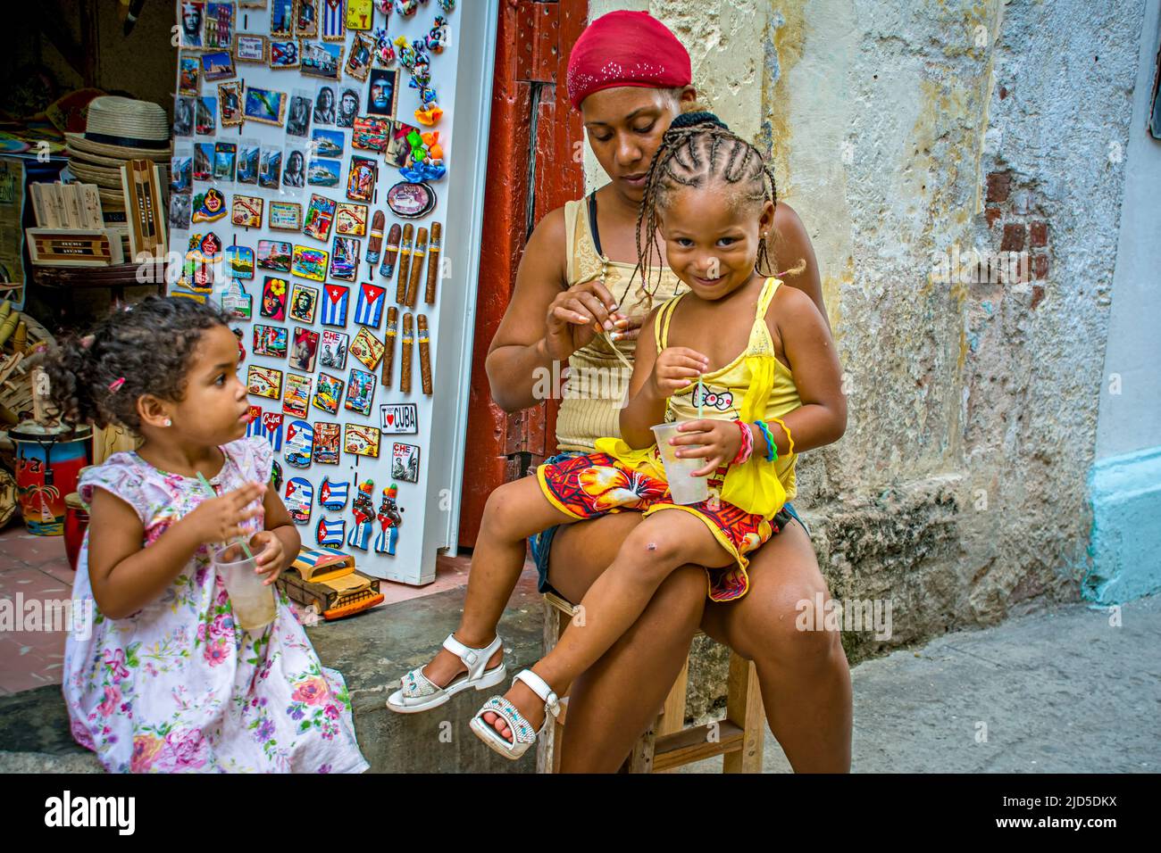 Donna con due ragazze all'esterno di un negozio a Old Havana, Cuba Foto Stock