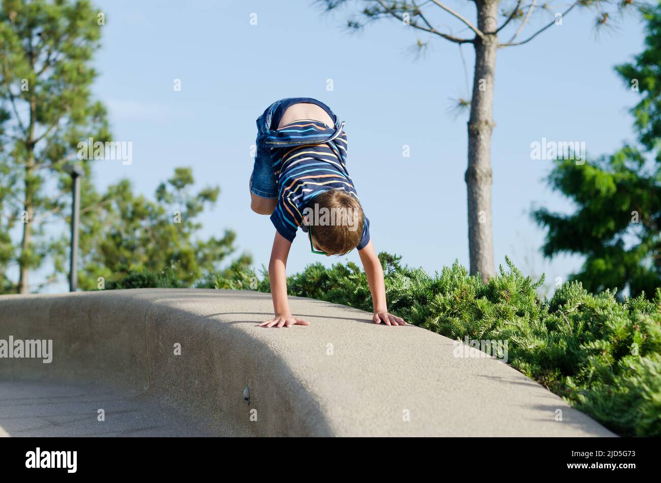 concetto di vacanza. bambino che guida scooter, a piedi nella città vecchia, strada. Risate in una giornata estiva di sole. Divertirsi Foto Stock