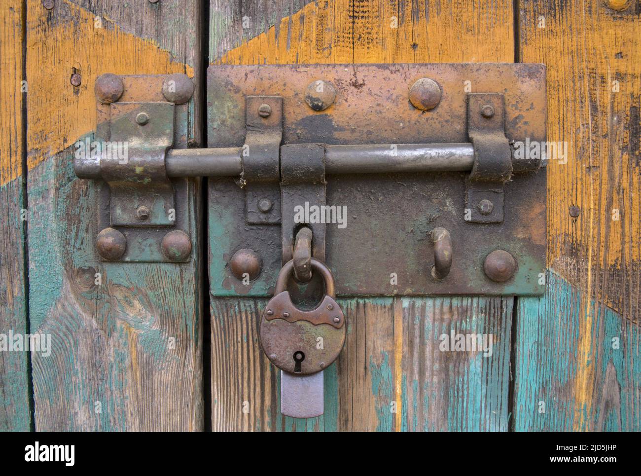 vecchio lucchetto in ferro sul cancello, vecchi assi in legno con vernice shabby, primo piano di un lucchetto appeso Foto Stock