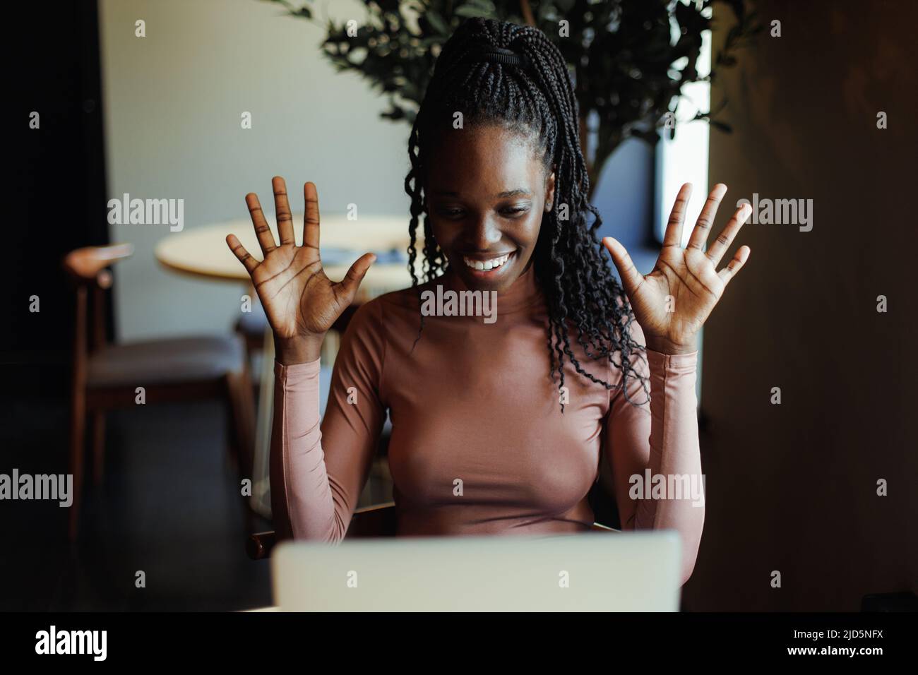 Gioiosa donna afroamericana emotivamente parlando gesturing su laptop online in caffetteria. Ragazza nera che lavora da remoto, freelance. Internet Foto Stock