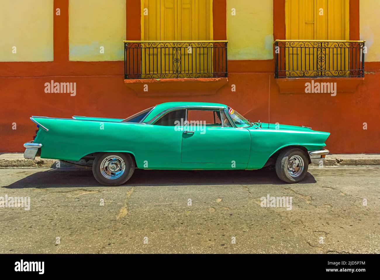 Bella auto d'epoca verde chiaro di fronte alla bella casa gialla/rossa per le strade di Santiago de Cuba, Cuba Foto Stock