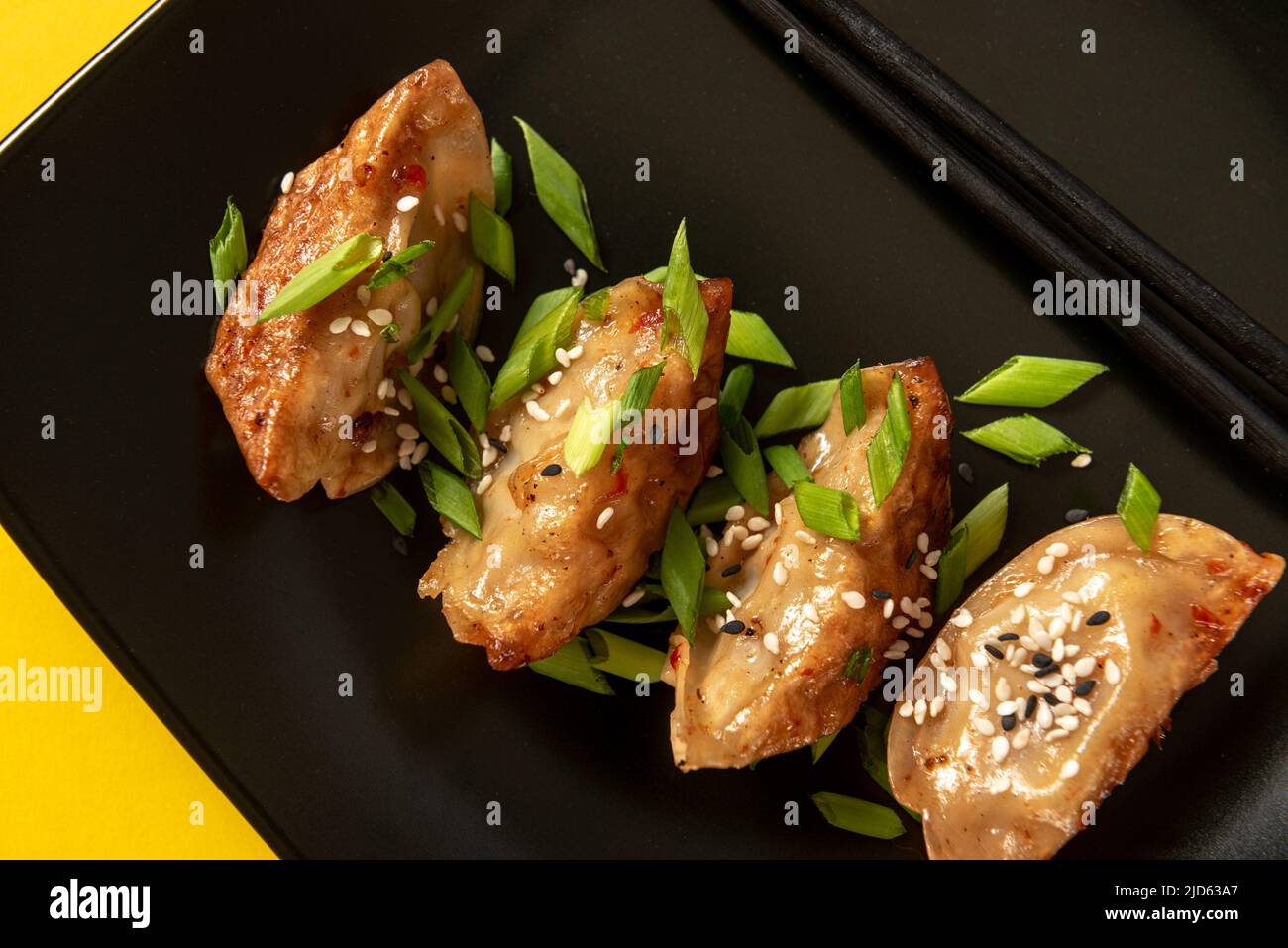 Gnocchi giapponesi originali Gyoza con pollo e verdure. Cucina tradizionale giapponese. Gnocchi fritti su sfondo giallo Foto Stock