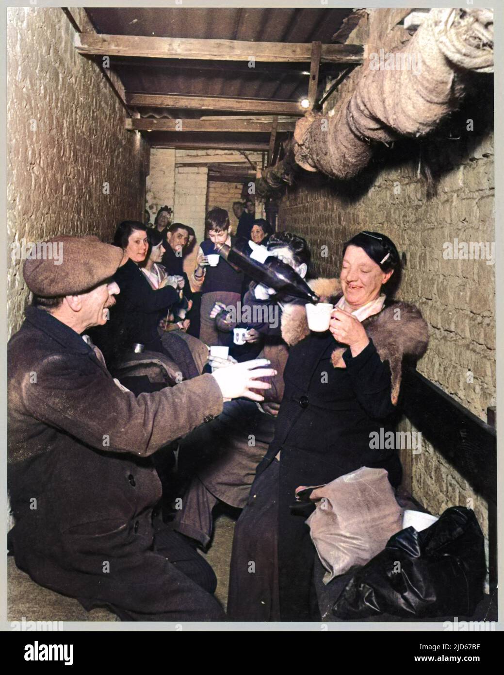 Sheltering sotterraneo durante il Blitz a Islington, Londra; una donna versa bevande per quelli intorno alla sua versione Colorizzata di : 10017003 Data: Nov-40 Foto Stock