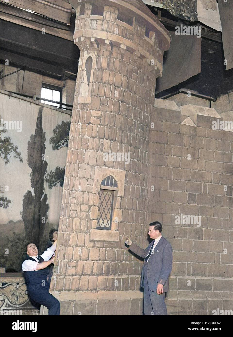 Un operaio di produzione teatrale tiene su una serie di palco di un castello per evitare che cada sul gestore di palco! Versione colorata di : 10164317 Data: Inizio 1930s Foto Stock